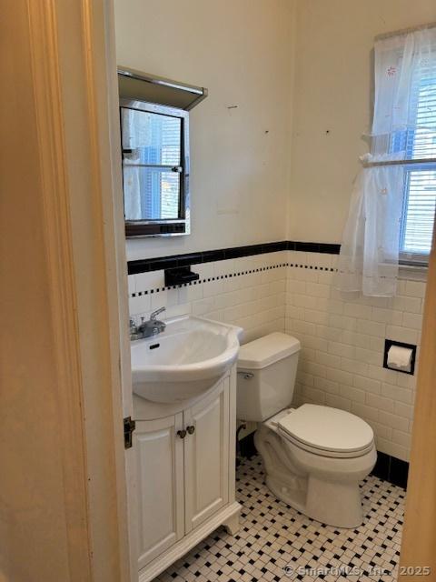94 Morris St, West Haven, CT 06516 - bathroom featuring tile patterned floors, vanity, tile walls, a wainscoted wall, and toilet