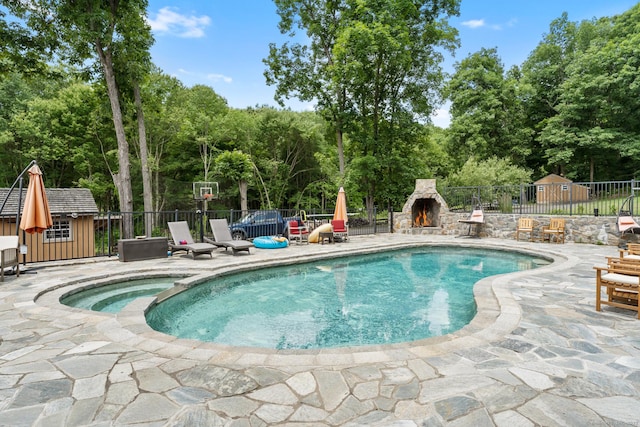 view of pool with fence, a patio area, and an outdoor stone fireplace
