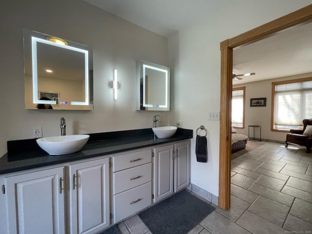 ensuite bathroom with connected bathroom, baseboards, a sink, and double vanity