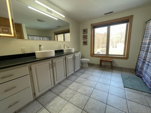 bathroom featuring toilet, tile patterned flooring, a sink, and visible vents