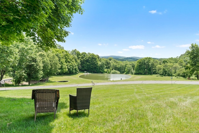view of community with a yard and a wooded view