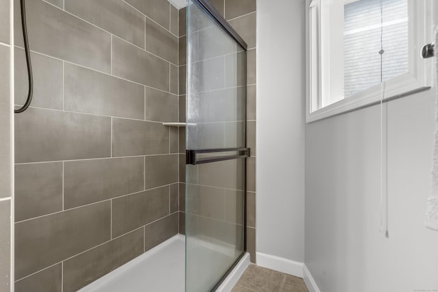 full bath featuring a shower stall and baseboards
