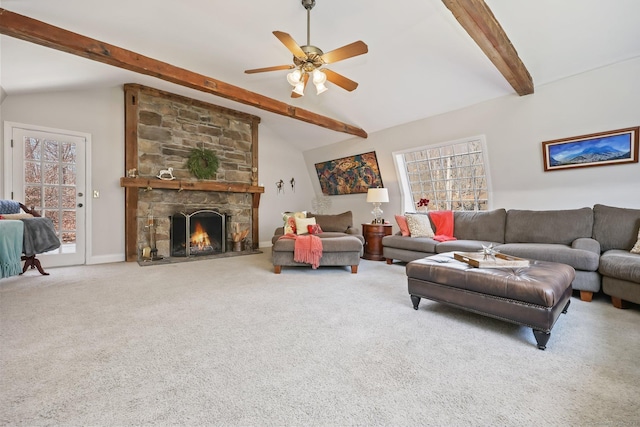 carpeted living area with a stone fireplace, ceiling fan, a wealth of natural light, and lofted ceiling with beams