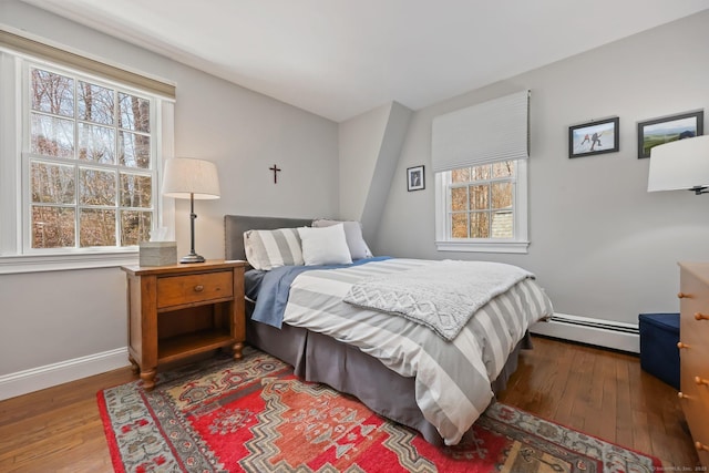 bedroom with baseboard heating, baseboards, and hardwood / wood-style flooring