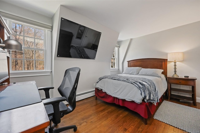 bedroom with baseboard heating, multiple windows, baseboards, and wood finished floors
