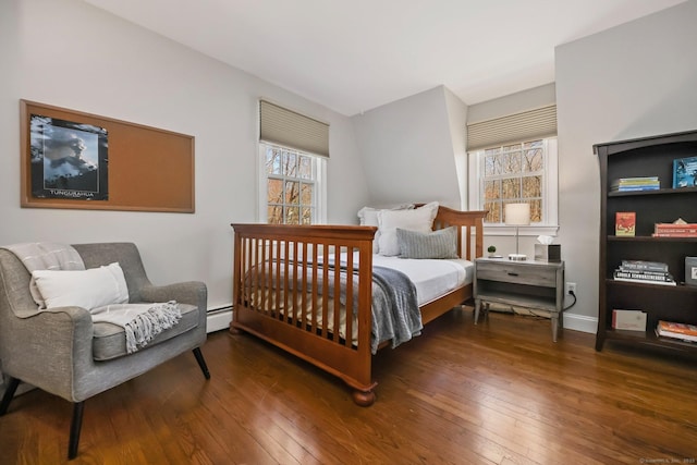 bedroom with baseboard heating, hardwood / wood-style floors, and baseboards