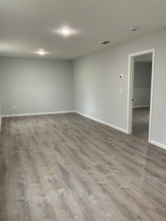 empty room featuring baseboards, dark wood-style flooring, and visible vents