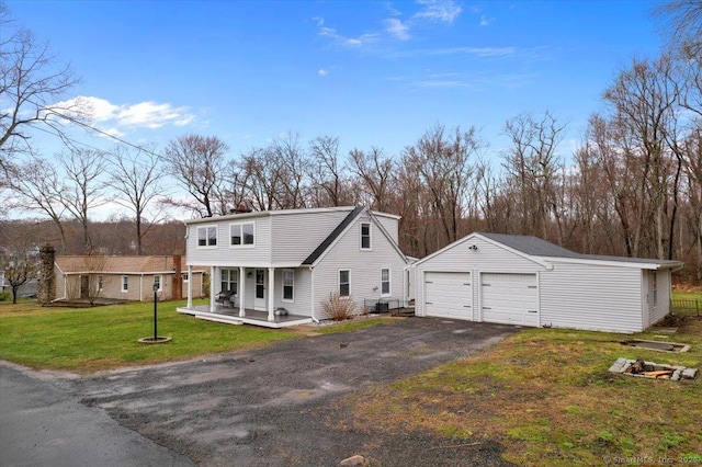 view of front of house with a porch, an outbuilding, a garage, and a front lawn