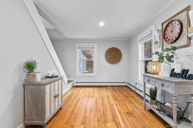 hall featuring ornamental molding, light wood-type flooring, plenty of natural light, and baseboard heating