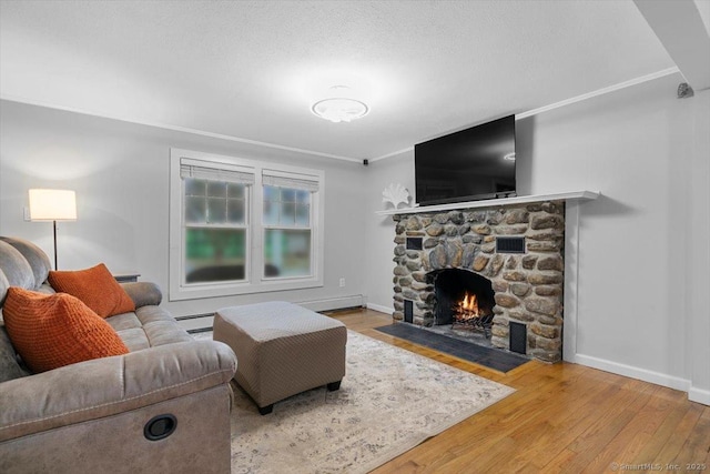 living area featuring a stone fireplace, baseboards, and wood finished floors