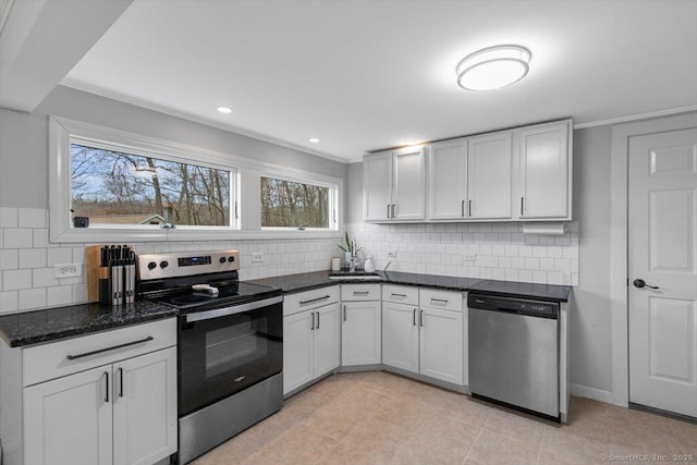 kitchen featuring stainless steel appliances, tasteful backsplash, ornamental molding, and dark stone counters