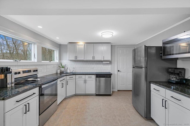 kitchen with dark stone counters, recessed lighting, appliances with stainless steel finishes, a sink, and backsplash