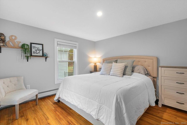 bedroom featuring wood finished floors and a baseboard heating unit