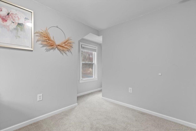carpeted empty room featuring baseboards
