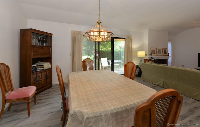 dining area featuring a notable chandelier, wood finished floors, and lofted ceiling