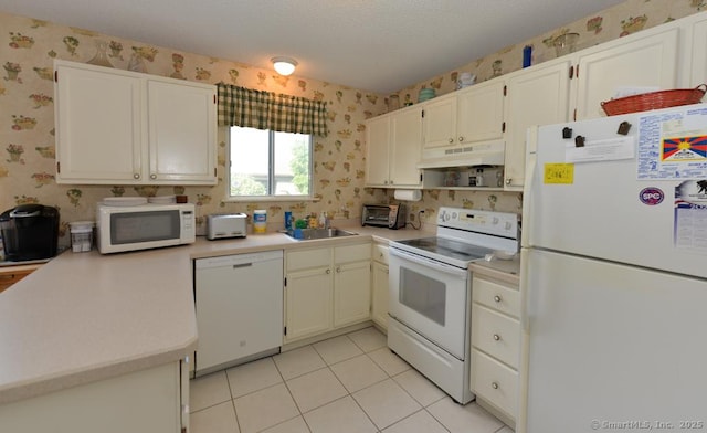 kitchen with light countertops, white appliances, under cabinet range hood, a textured ceiling, and wallpapered walls