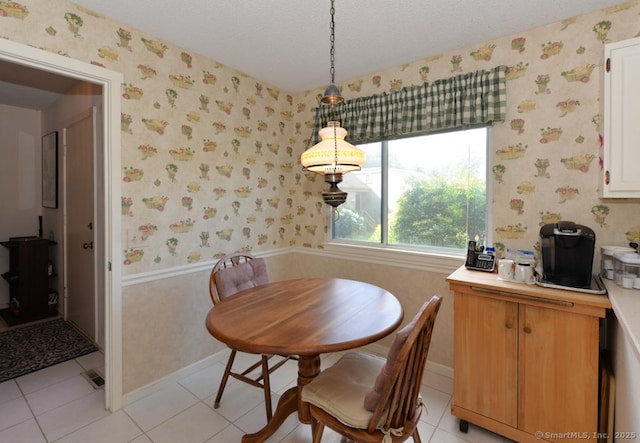 dining room featuring a textured ceiling, wallpapered walls, and light tile patterned floors