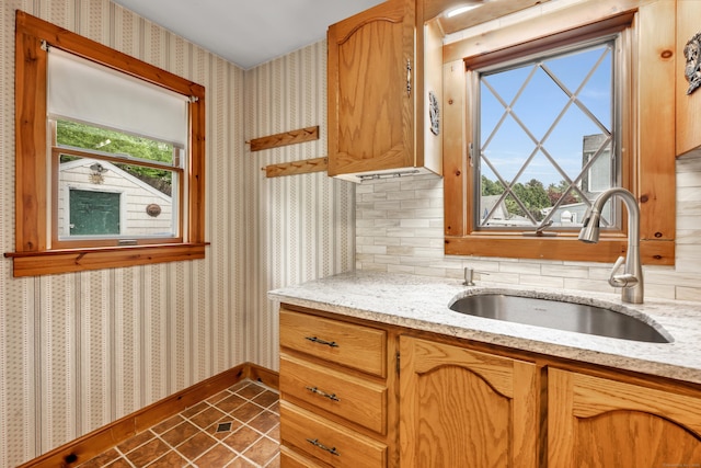 39 Smith St, Bristol, CT 06010 - kitchen featuring wallpapered walls, a sink, baseboards, light stone countertops, and dark tile patterned floors