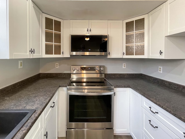 kitchen with appliances with stainless steel finishes, dark countertops, and white cabinets