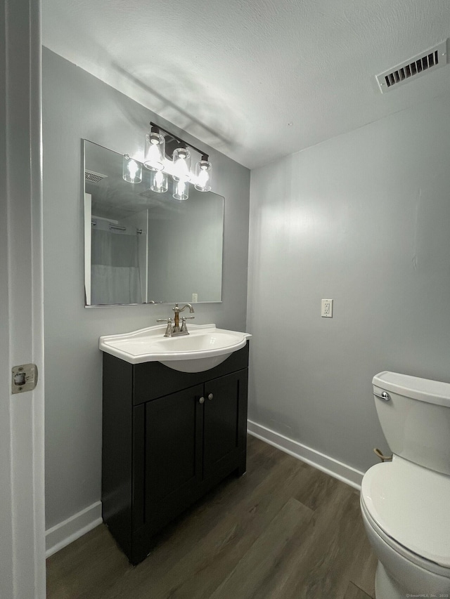 bathroom with vanity, baseboards, toilet, visible vents, and wood finished floors