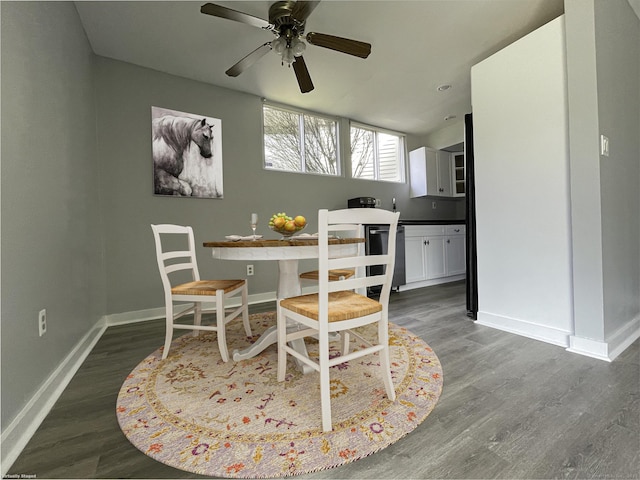 dining space with ceiling fan, baseboards, and dark wood finished floors