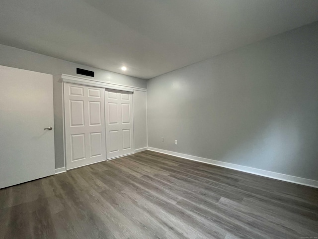 unfurnished bedroom featuring a closet, dark wood-style flooring, baseboards, and recessed lighting