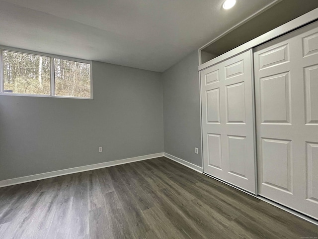 unfurnished bedroom with a closet, baseboards, and dark wood finished floors