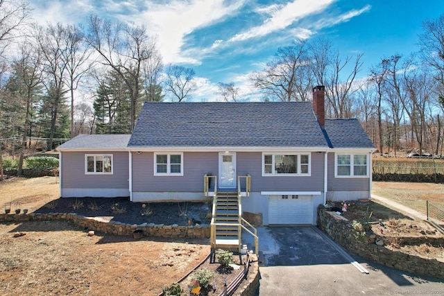 view of front of property featuring driveway, a chimney, roof with shingles, and a garage