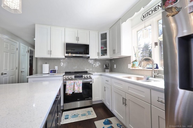 kitchen with decorative backsplash, stainless steel appliances, a sink, and white cabinetry