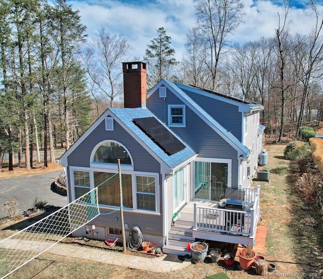 back of house featuring a chimney, a wooden deck, and central AC unit