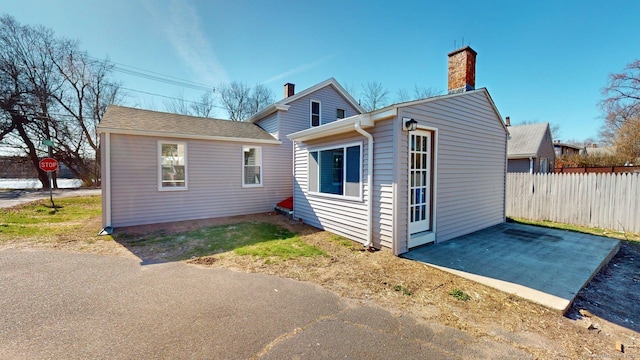 exterior space with fence, a patio area, and a chimney