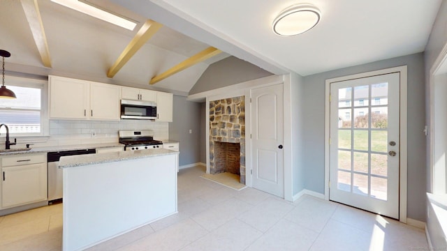 kitchen with tasteful backsplash, a sink, vaulted ceiling with beams, stainless steel appliances, and baseboards