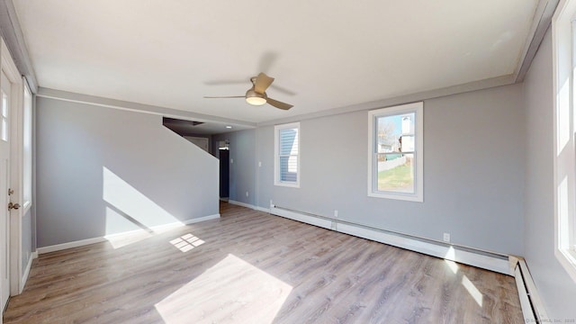 unfurnished room with baseboard heating, ceiling fan, baseboards, and light wood finished floors