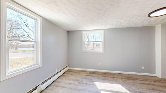 unfurnished room featuring baseboard heating, baseboards, a textured ceiling, and light wood-style floors