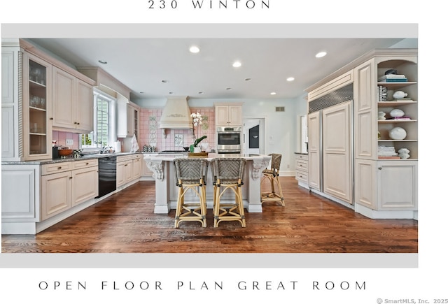 kitchen featuring a breakfast bar, glass insert cabinets, premium range hood, dark wood finished floors, and a kitchen island