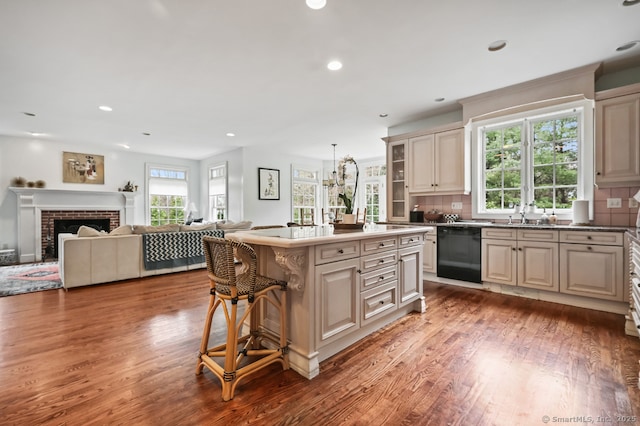 kitchen with dishwasher, decorative backsplash, cream cabinets, and wood finished floors