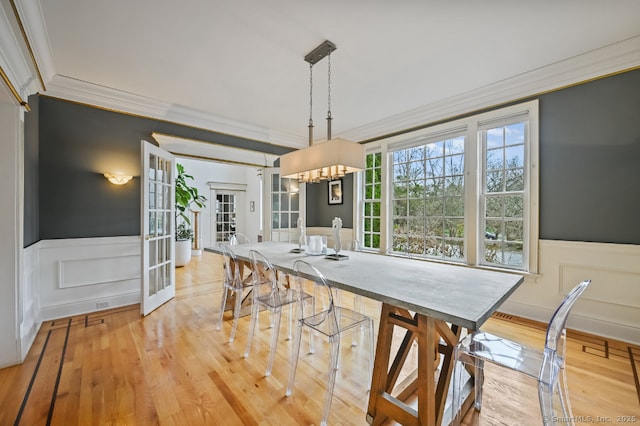 dining room with wainscoting, a decorative wall, and ornamental molding