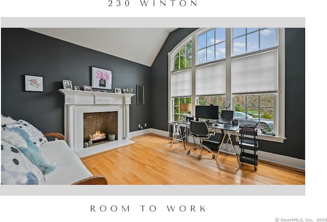 office space featuring lofted ceiling, wood finished floors, and a fireplace with flush hearth