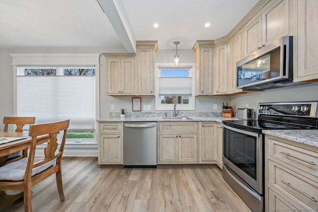 76 Carriage Path S Unit 76, Milford, CT 06460 - kitchen featuring light wood-type flooring, stainless steel appliances, cream cabinets, a sink, and light stone countertops