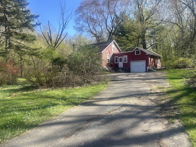 view of side of property with aphalt driveway, a yard, and an attached garage