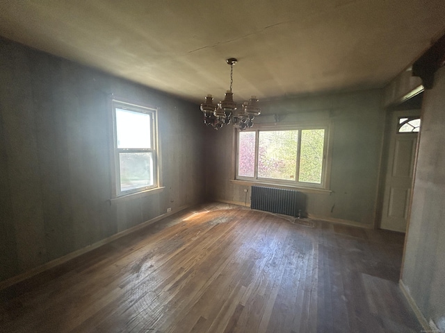 unfurnished dining area with hardwood / wood-style floors, radiator, a chandelier, and a wealth of natural light