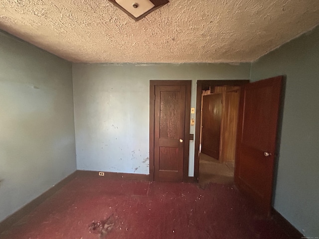 unfurnished room featuring a textured ceiling, carpet floors, and baseboards