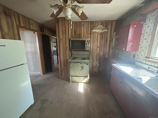 kitchen featuring wooden walls, a ceiling fan, brown cabinetry, and white appliances
