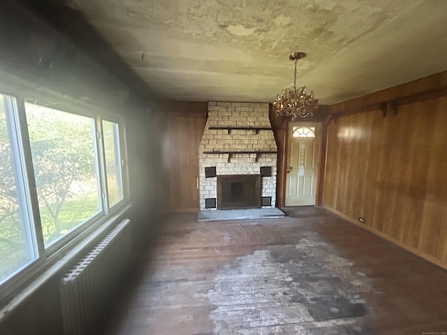 unfurnished living room featuring wood walls, radiator heating unit, and a healthy amount of sunlight