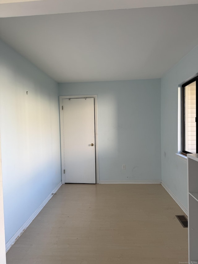spare room featuring baseboards, light wood-style flooring, and visible vents