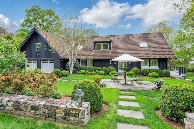 back of house featuring a yard, board and batten siding, a tiled roof, a garage, and a patio area