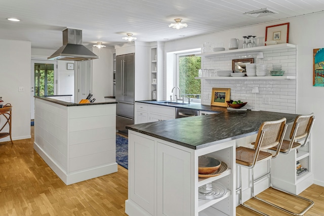 kitchen with visible vents, a sink, island exhaust hood, open shelves, and dark countertops