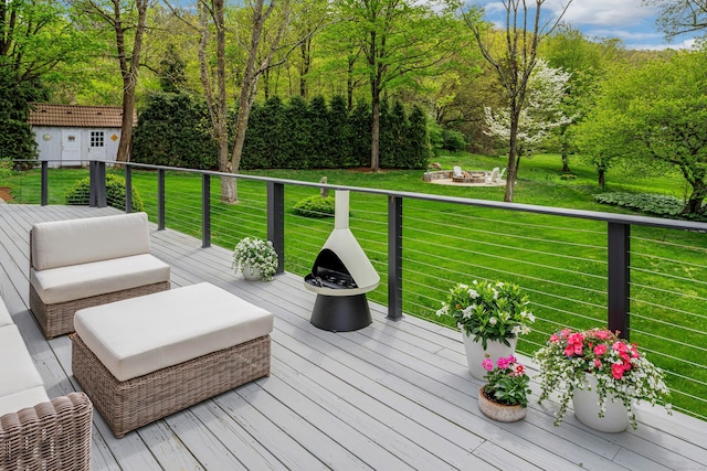 wooden deck with a yard, an outdoor fire pit, and an outbuilding