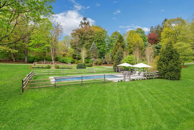 view of community featuring a lawn and fence