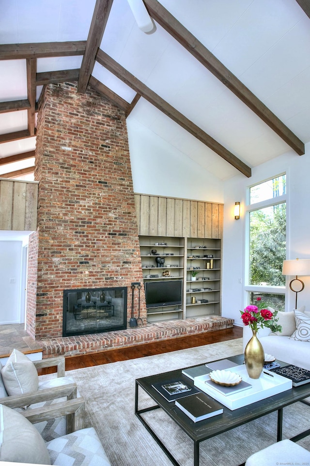 living room with high vaulted ceiling, a fireplace, and beamed ceiling